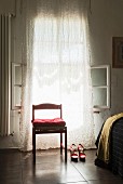 Cushion on red chair and red high-heeled shoes in front of window