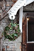 Wreath of willow and green ivy tendrils hung from white porch roof