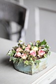 Romantic arrangement of ivy and roses in vintage container