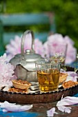 Almond tarts, metal kettle and glass of tea in old tart tin