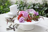 Small cake decorated with flowers and berries on table set for afternoon coffee