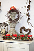 Adventsgesteck mit sternförmigen Kerzen auf einem Stück Rinde