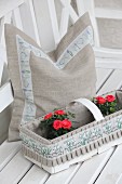 Cushion cover hand made from undyed linen with floral trim behind roses in decorated chip wood basket