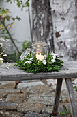 Lit candle in mason jar in wreath of box and honesty