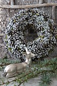 Doe ornament and larch twigs in front of wreath of pine cones and moss