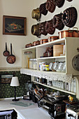 Old cake tins and pans on wall above shelves in kitchen