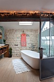 Exposed stone wall and oval free-standing bathtub in bathroom