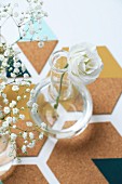 Delicate white rose and gypsophila in glass vases on hand-made cork coasters