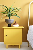 Yucca in retro pot on bedside cabinet painted yellow