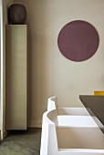 White designer chair below round mauve circle on wall