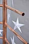 Paper stars hung from stylised Christmas tree hand-made from copper piping