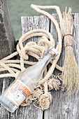 Swing-top bottle, natural cord and twigs on weathered wooden jetty
