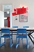 Red designer lamp above dining table and blue chairs