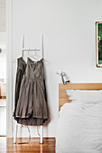 Graue Kleider hängen an einer Leiter neben dem Bett