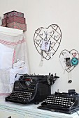 Vintage black typewriters below wire love-hearts on wall used as pinboards