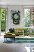 Green sofa on blue rug in front of floor-to-ceiling windows