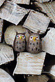 Hand-made, needle-felted, woollen owls on stacked firewood