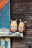 Two hand-made, felted, woollen owls against wooden background
