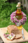 Bottle decorated with wreath of flowers and bread on wooden board