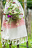 Bouquet of wildflowers and cotton towel hung on garden fence