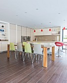 Modern dining table and colourful chairs in open-plan kitchen