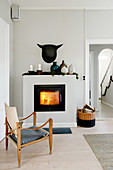 Old designer chair in front of lit fire in square stove
