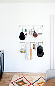 Pots and pans hung from metal rods on white kitchen wall