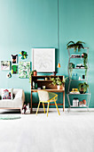 Secretary with armchair, open shelf with house plants and sofa against green wall