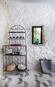 Ornate metal shelves next to small window in plastered stone wall
