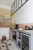 Concrete counter in kitchen with layers of old paint on wall