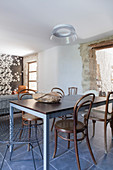 Various chairs around dining table in front of doorway in stone wall