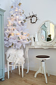 Christmas tree decorated with vintage photos next to dressing table