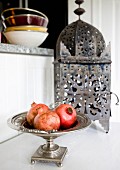 Pomegranates in silver dish in front of Oriental lantern