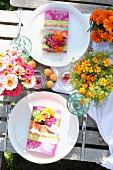 Sommerliches Gedeck für Zwei mit farbenfrohen Blumensträusschen auf rustikalem Gartentisch