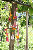 Blumendekoration in Campari-Fläschchen an Vintage Metallgestell aufgehängt