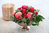 Festliches Weihnachtsgesteck mit Rosen, Granatäpfeln und Efeuranken