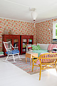Colourful, eclectic mixture of furniture in living room with floral wallpaper