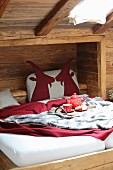 Bettkopfteil mit Tiermotiven aus rotem Filz in rustikaler Bettnische