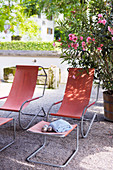 Two red loungers with footstools on summery gravel terrace