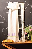 Pastries, carafe, vase of tulips and vintage window frame with curtain against chalkboard wall