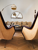 Two retro armchairs in front of coffee table and beige sofa
