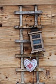 Rankgitter mit Laterne und Herzform an Holzfassade