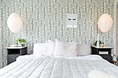 Quilt on bed against wallpaper with pattern of cotton plants