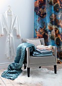 Dressing corner in white room with blue blanket and bed linen on chair