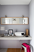 Basin and accessories on washstand below mirrored cabinet in bathroom
