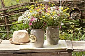 Bouquets of wild cow parsley, red campion and buttercups in two stone jars on garden bench