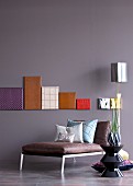 Canvases covered in high-tech fabrics on painted wall above leather couch and ceramic side table