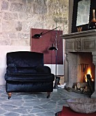 Black velvet armchair next to open fire in historical ambiance