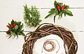 Red chillies, sage leaves, rosemary and willow wreath on white surface
