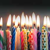 Colourful lit birthday-cake candles (close-up)